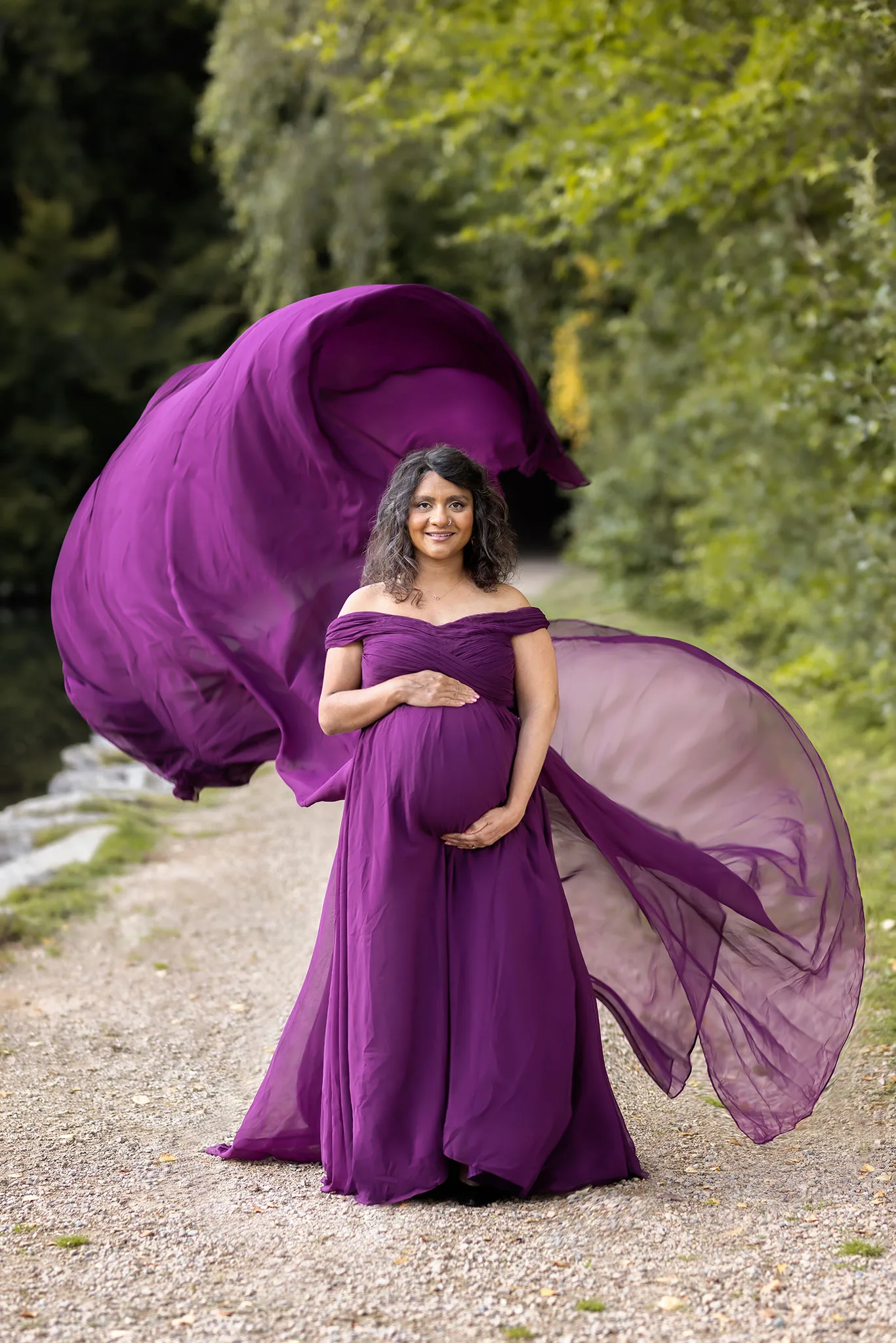 Gravidfotografering utomhus i Skåne med en mamma i lila böljande klänning.