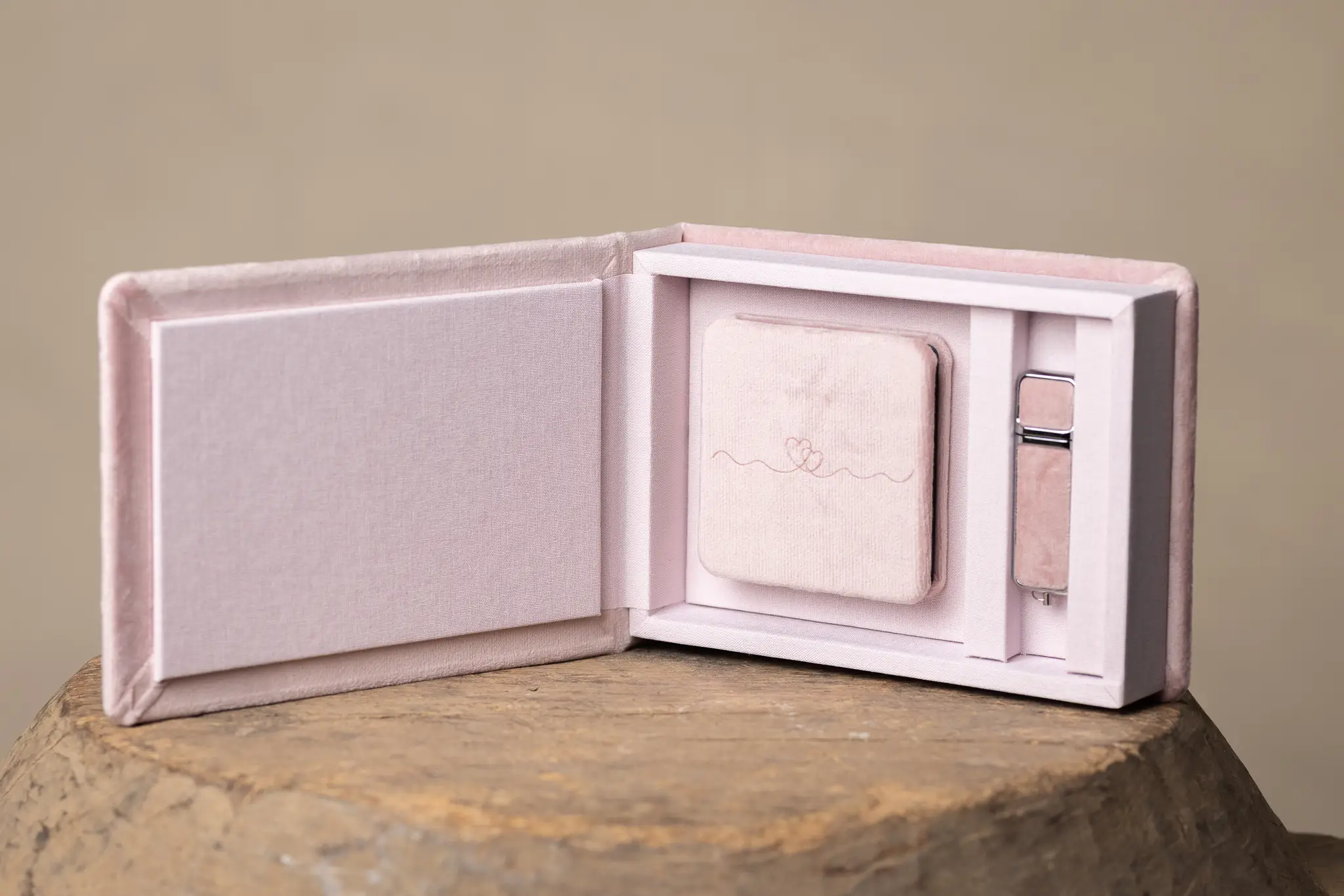 Rosa fotobox för babybilder Rosa sammetsbox med litet minialbum och USB-minne på träunderlag.