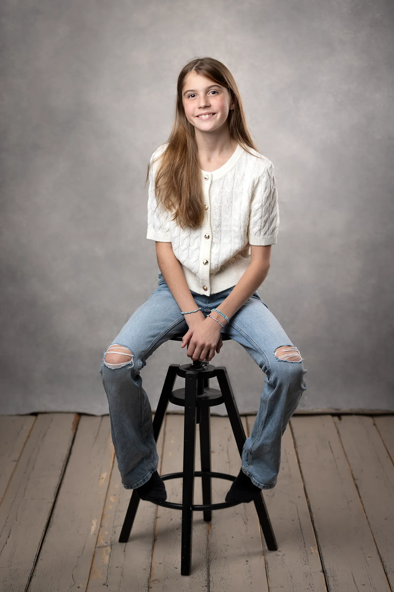 Äldre barn i studion – porträttfotografering Porträtt av äldre barn i studion, sittande på en pall med neutralt bakgrund.