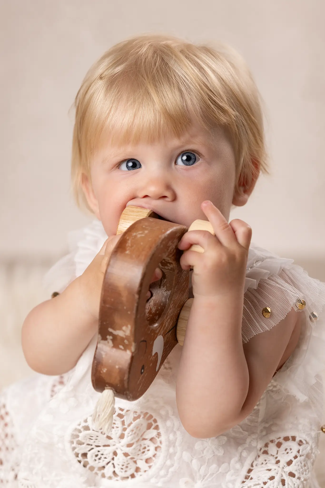 Babyfotograf Lund - Baby flicka smakar på en träelefant.