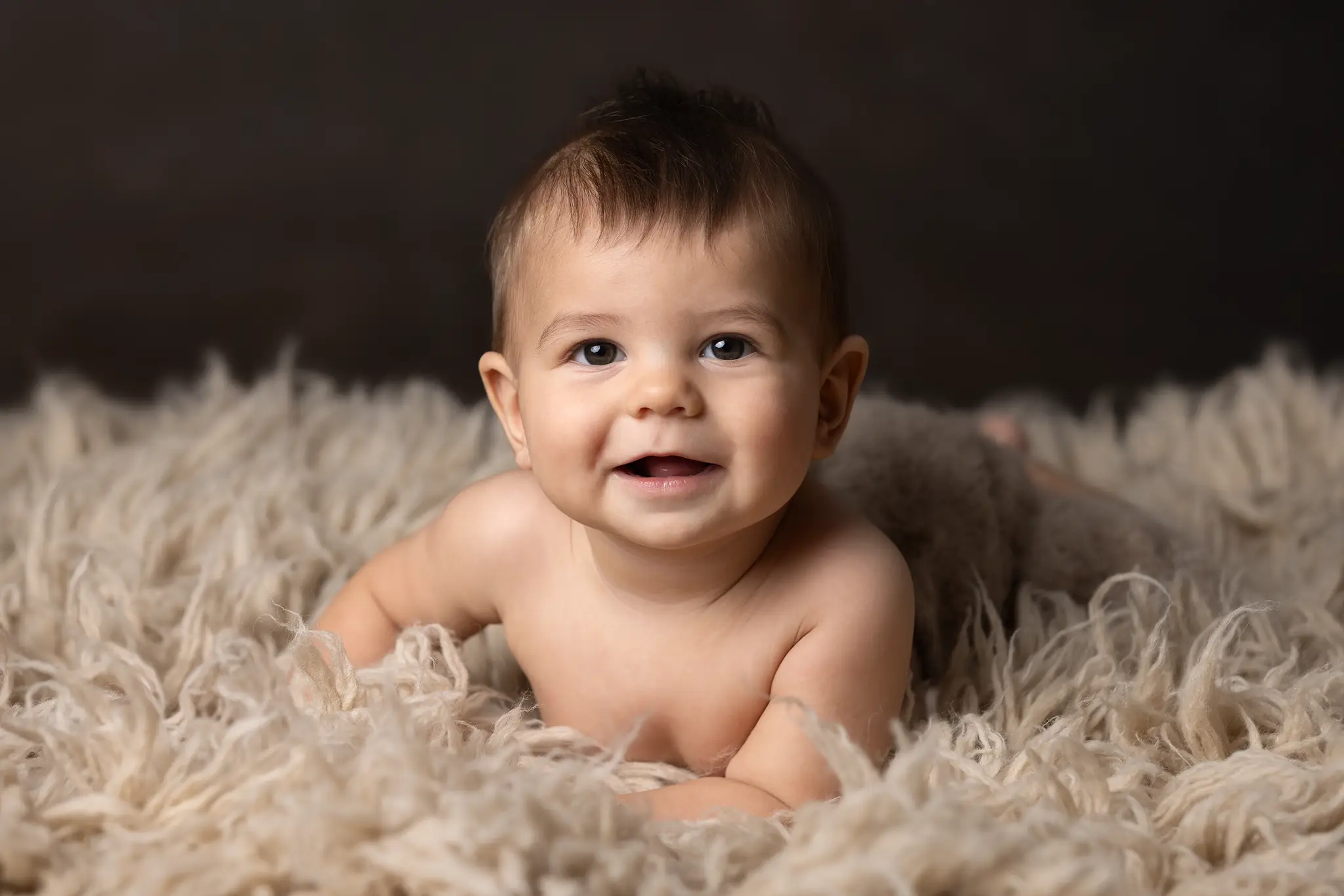 Liten baby på fluffig fäll. Liten baby på mage på fluffig fäll.