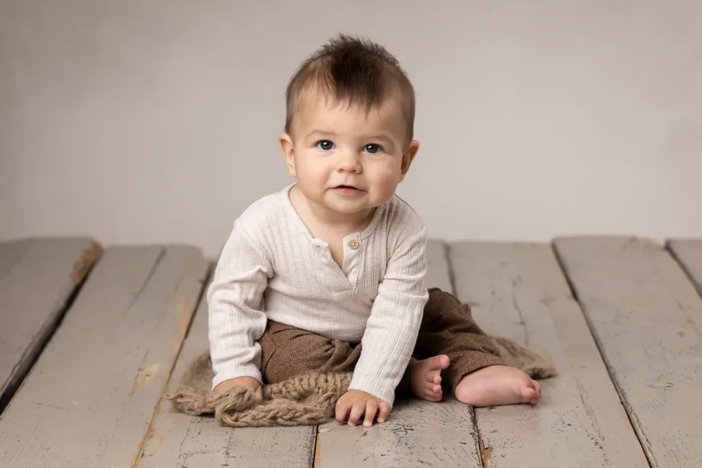 Babyfotograf Lund - Baby pojke sitter på trägolvet.