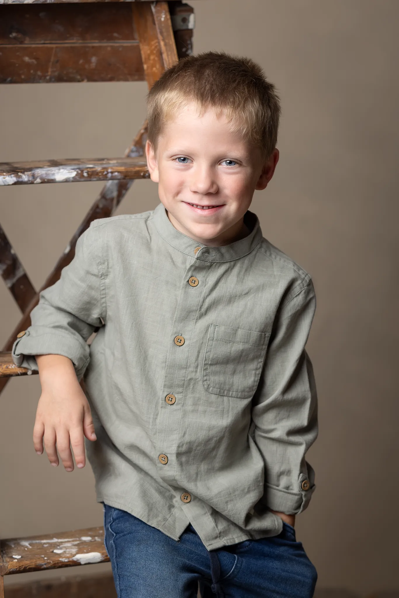 En pojke i grön skjorta lutar sig på en stege. En pojke i grön skjorta lutar sig på en stege.