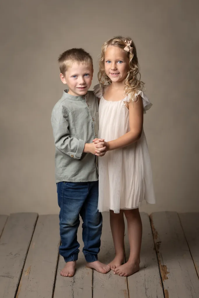 Ett tvillingpar kramar varandra under en fotografering.