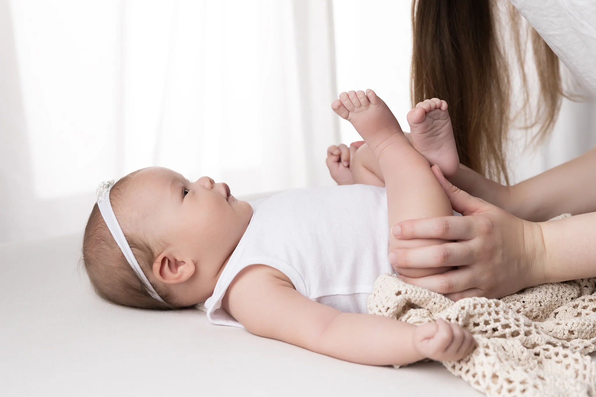 2 månader gammal bebis fotograferad i studio i Lund med föräldrahänder som skapar trygghet