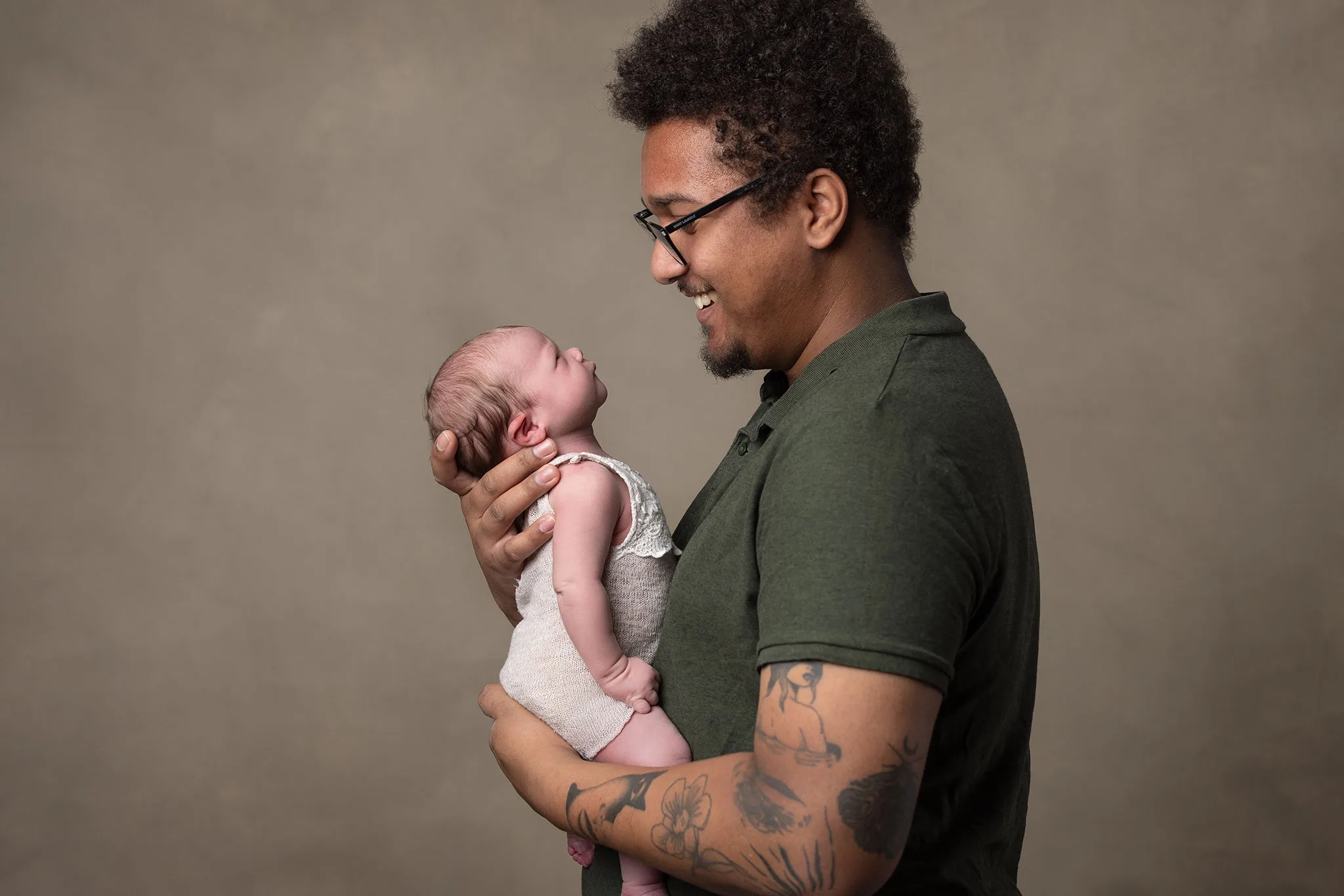 Pappa håller sin nyfödda bebis under bebisfotografering lund