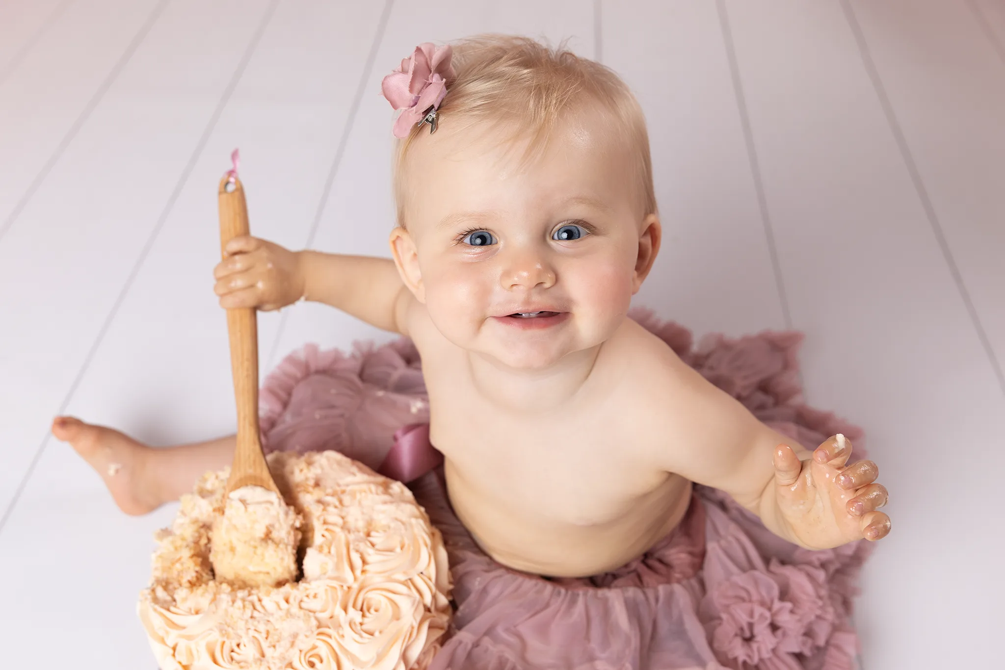 smash-the-cake-lund-1-arsfotografering-flicka-slev-tarta mash the Cake-fotografering i Lund med 1-åring som ler och håller en slev vid tårtan