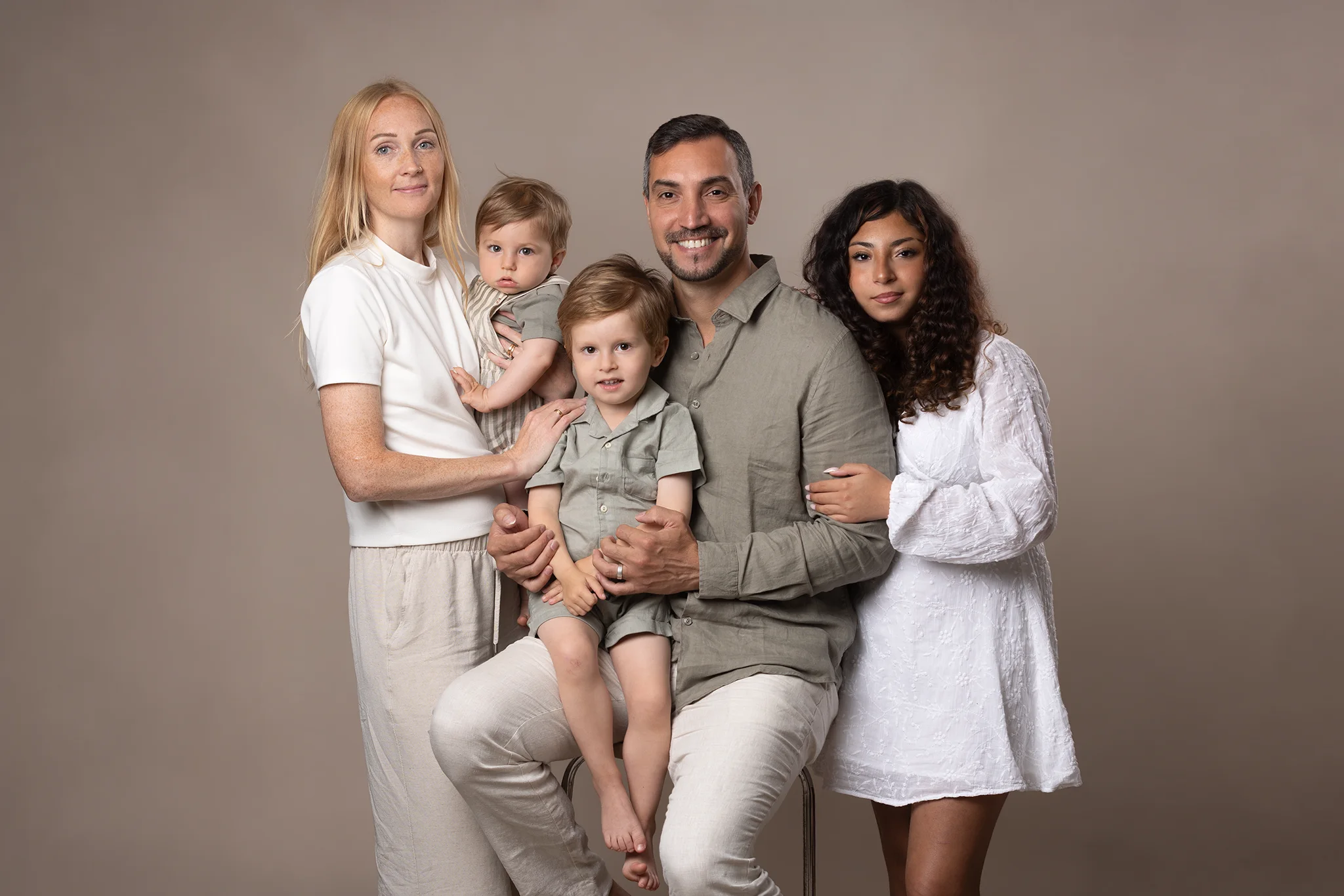 Familj på fem personer fotograferad tillsammans i studio i Lund.