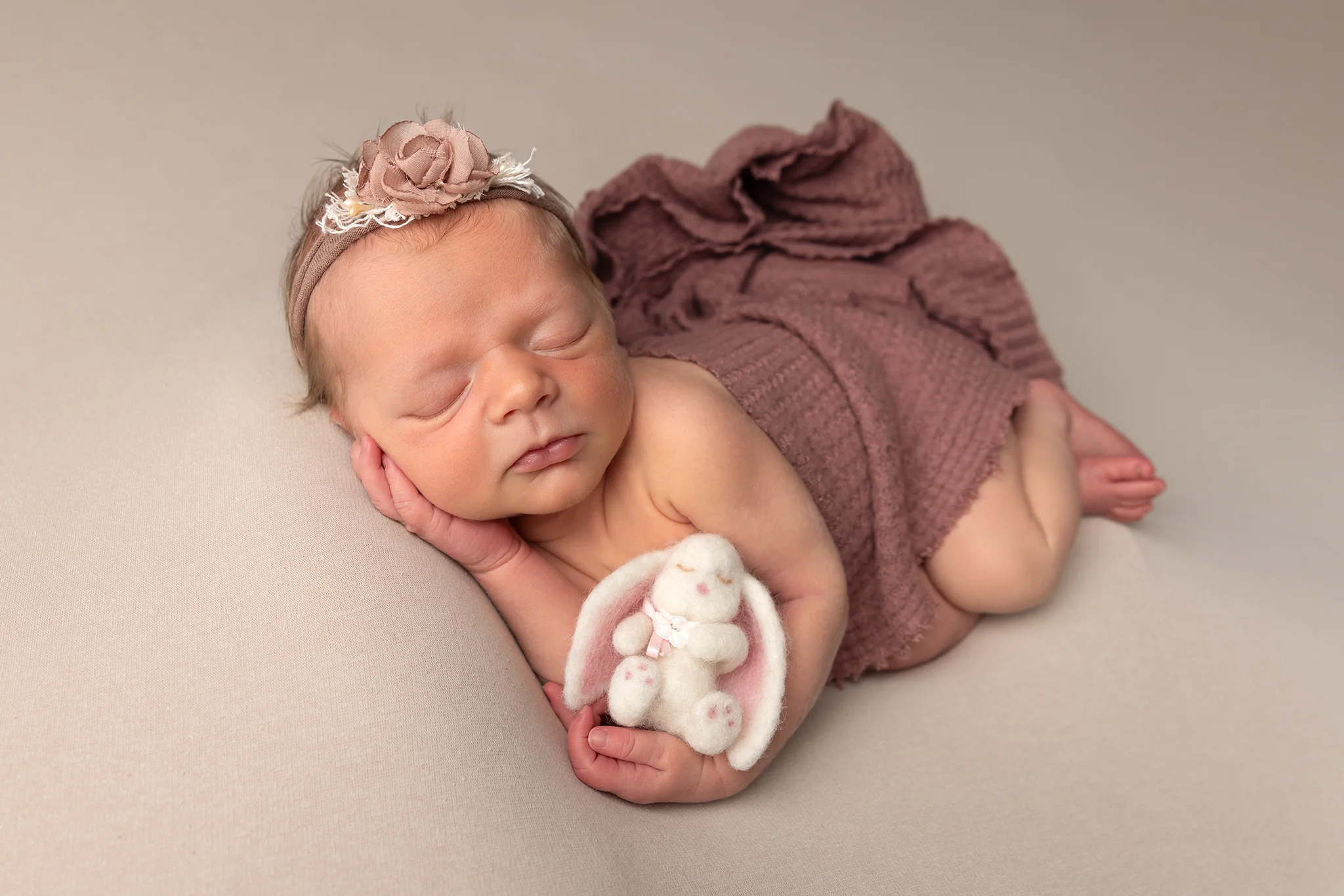 nyfoddfotograf-lund-nyfodd-baby-kanin Sovande nyfödd flicka med en liten kanin under en nyföddfotografering i studio hos Fotograf Suzanna K i Lund.
