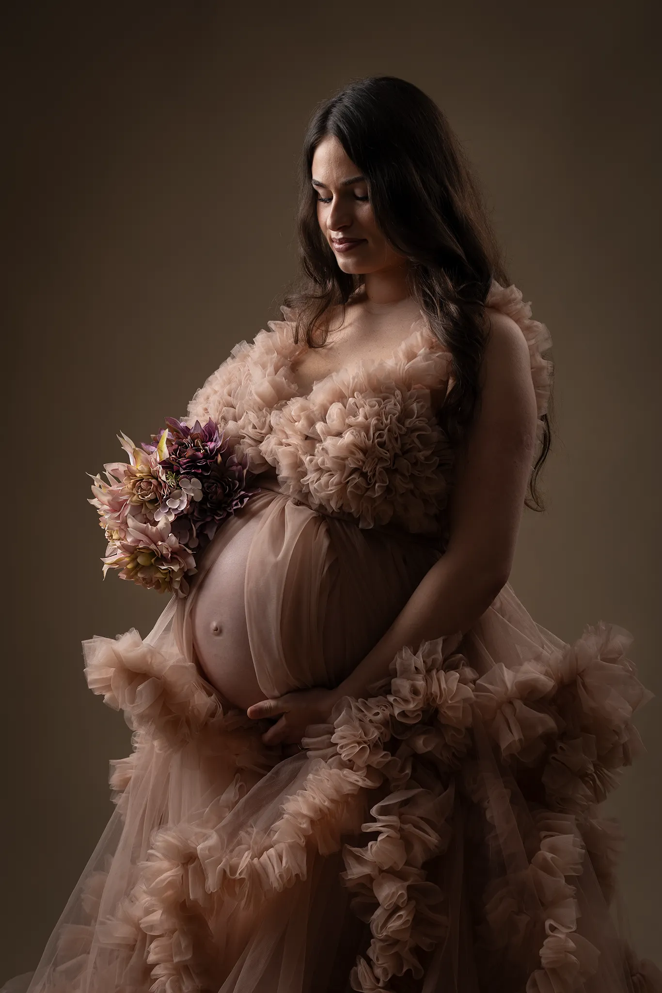 Gravid kvinna i rosa tyllklänning under gravidfotografering i studio i Lund