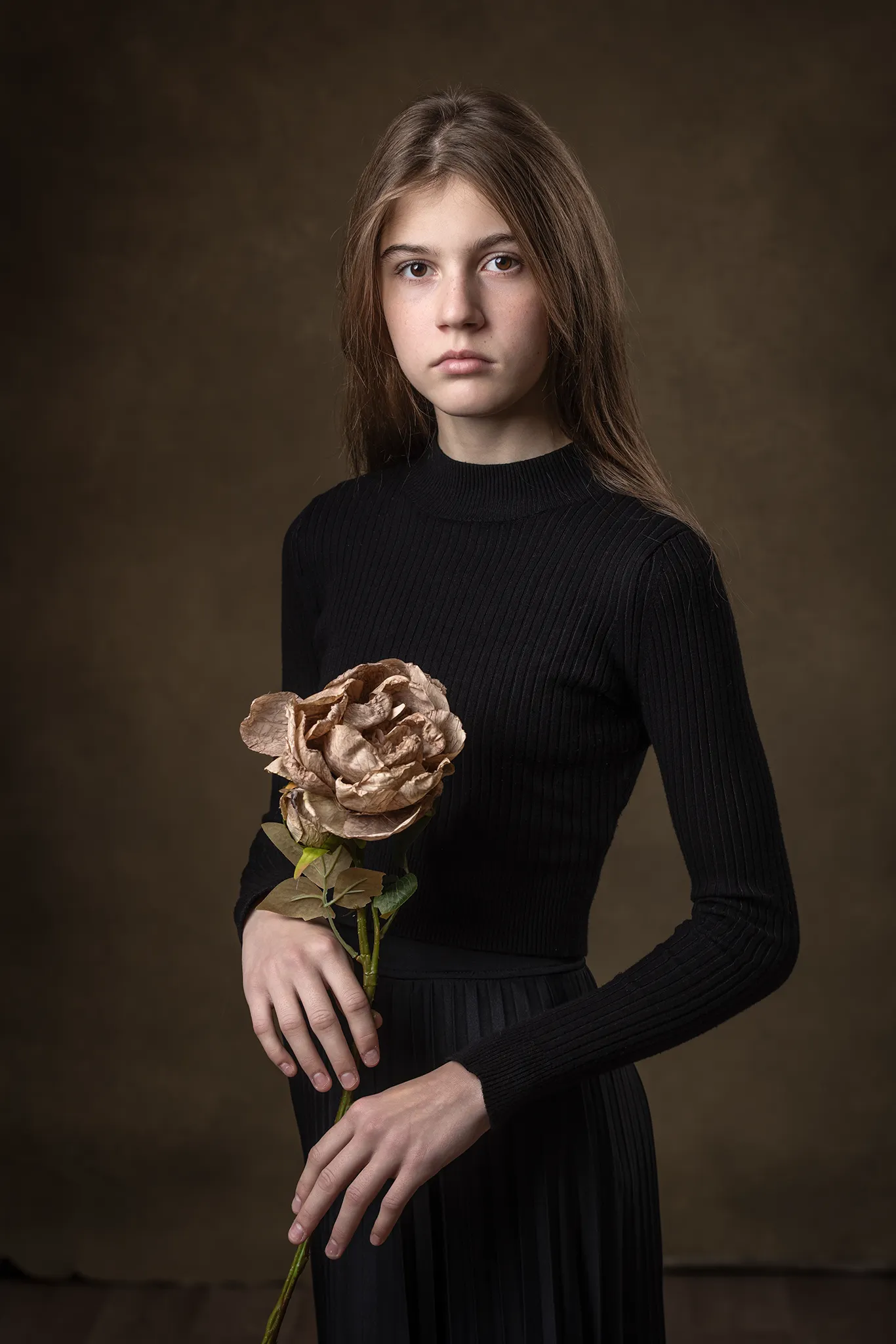 Ung flicka håller en blomma i handen.